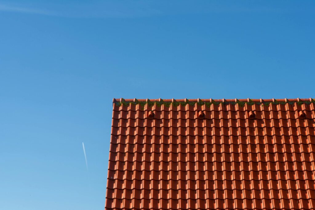Minimalist photo of a red tiled rooftop contrasting against a clear blue sky.